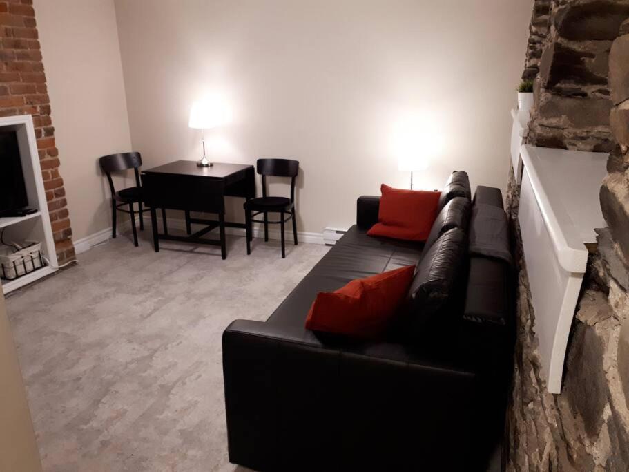 ein Wohnzimmer mit einem schwarzen Sofa und einem Tisch in der Unterkunft Bauer Terrace - Cozy 1 bedroom beside The Citadel in Halifax