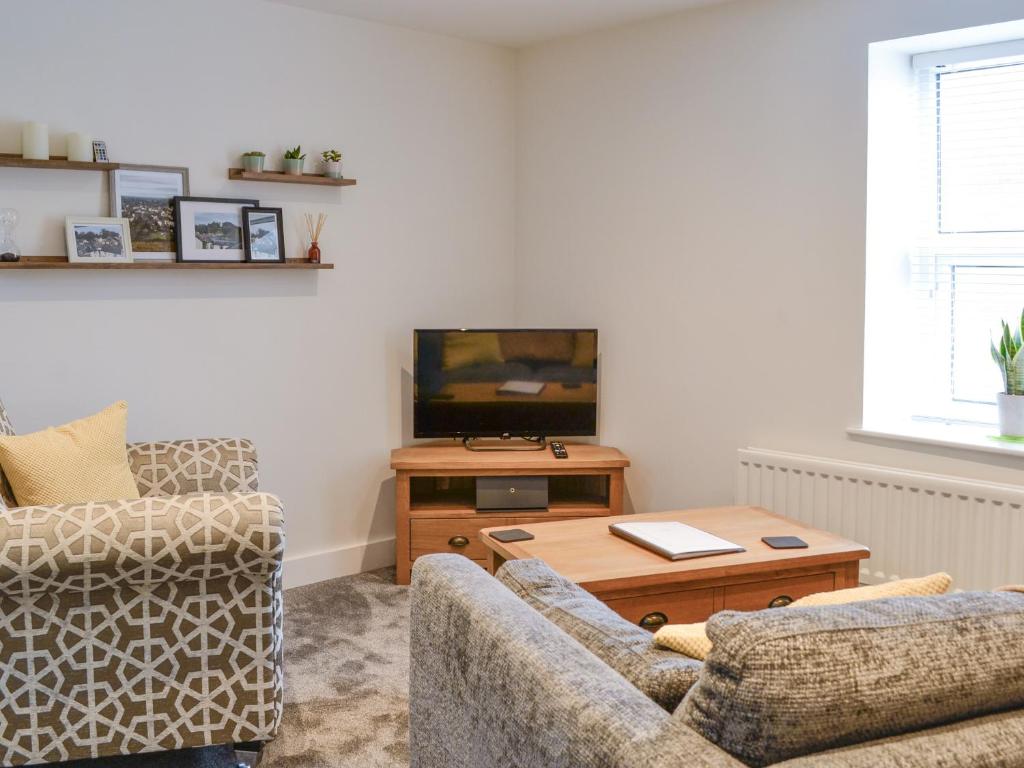 uma sala de estar com um sofá e uma mesa com uma televisão em Moat View em Brampton