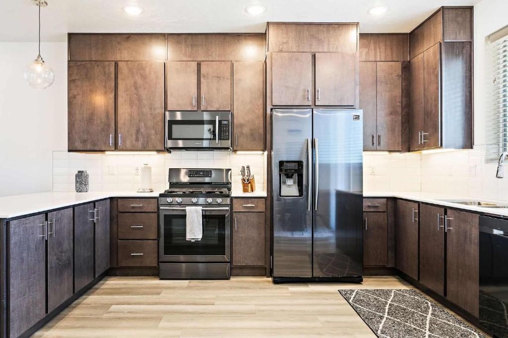 une cuisine avec des armoires en bois et des appareils en acier inoxydable dans l'établissement Sunrise Corner #43 townhouse, à Saint George