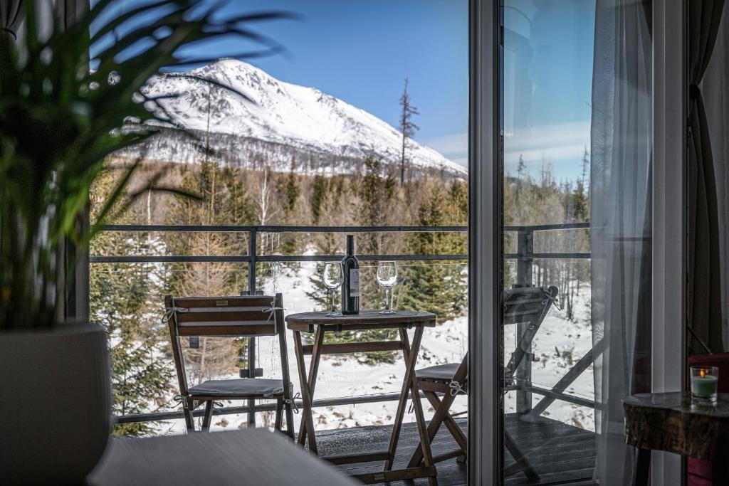 a balcony with a table and chairs and a snow covered mountain at Apartman pod Gerlachom s wellness in Vysoke Tatry - Horny Smokovec