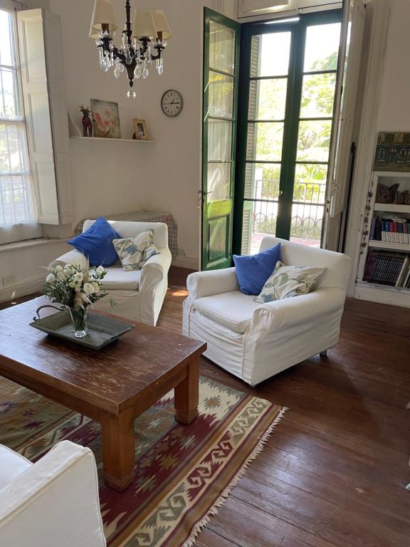 Departamento Malva con gran jardín في سان إيسيدرو: غرفة معيشة مع كنبتين بيضاء وطاولة قهوة