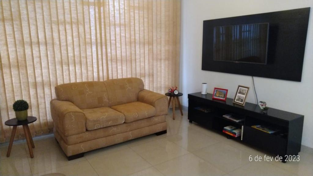 un sofá de cuero marrón en una sala de estar con TV en Apartamento Uberlândia - Centro com garagem, en Uberlândia