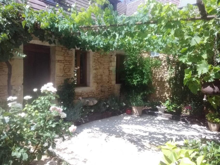 einen Garten mit einem Backsteingebäude mit Bäumen und Blumen in der Unterkunft Petite maison de caractère in Le Bousquet
