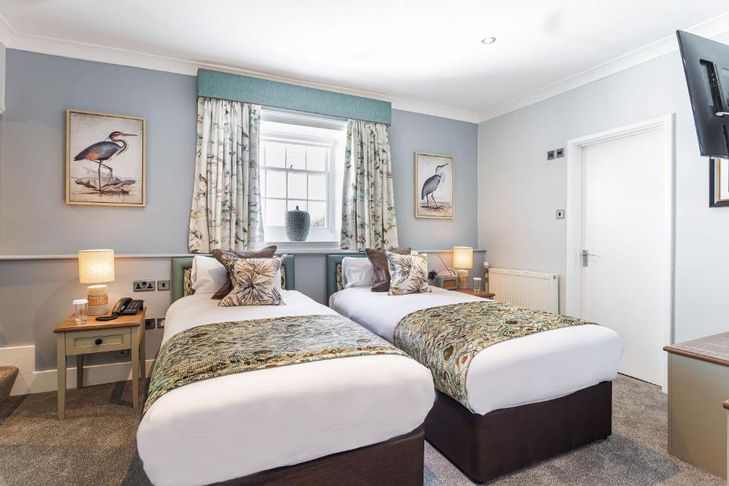 a hotel room with two beds and a window at The Manor Coastal Hotel & Inn, Blakeney - part of The Coaching Inn Group in Blakeney
