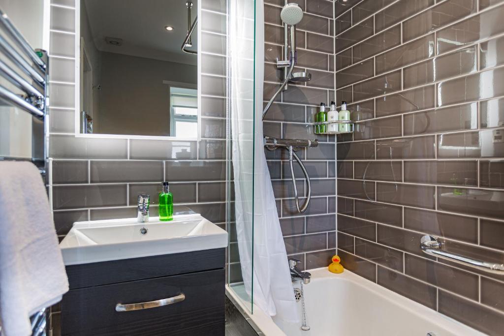 a bathroom with a sink and a shower and a tub at The Manor Coastal Hotel & Inn, Blakeney - part of The Coaching Inn Group in Blakeney