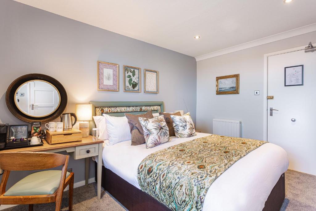 a bedroom with a bed and a desk and a mirror at The Manor Coastal Hotel & Inn, Blakeney - part of The Coaching Inn Group in Blakeney