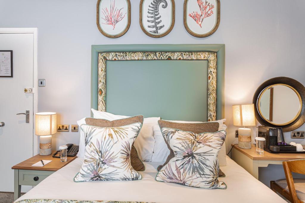 a bedroom with a bed with pillows and a mirror at The Manor Coastal Hotel & Inn, Blakeney - part of The Coaching Inn Group in Blakeney