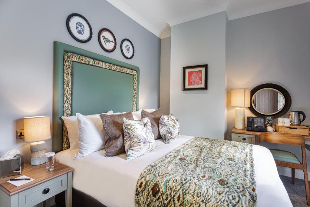 a bedroom with a large bed with a mirror on the wall at The Manor Coastal Hotel & Inn, Blakeney - part of The Coaching Inn Group in Blakeney