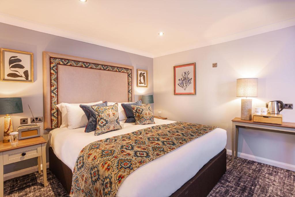 a hotel room with a large bed and a fireplace at The Manor Coastal Hotel & Inn, Blakeney - part of The Coaching Inn Group in Blakeney