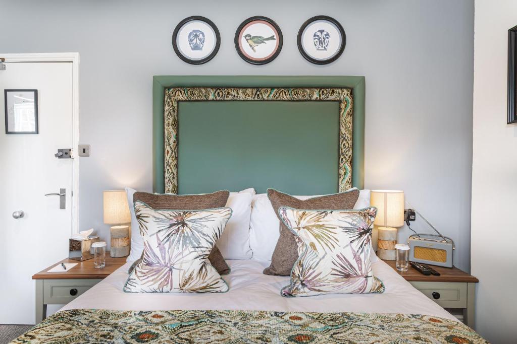 a bedroom with a large bed with three clocks on the wall at The Manor Coastal Hotel & Inn, Blakeney - part of The Coaching Inn Group in Blakeney