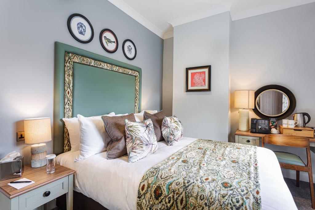 a bedroom with a bed with a large mirror on the wall at The Manor Coastal Hotel & Inn, Blakeney - part of The Coaching Inn Group in Blakeney