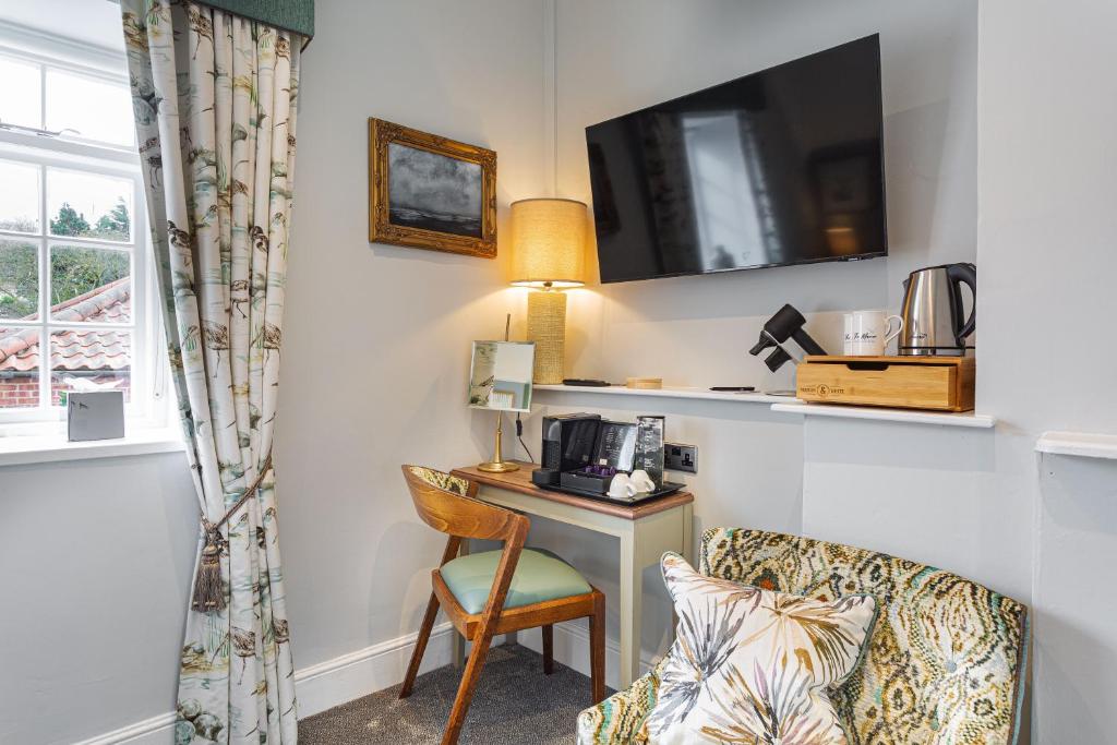 a hotel room with a desk and a chair and a table at The Manor Coastal Hotel & Inn, Blakeney - part of The Coaching Inn Group in Blakeney