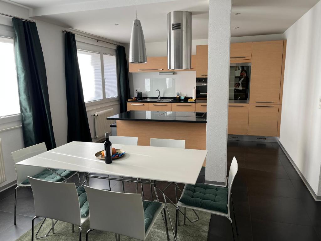 une salle à manger et une cuisine avec une table et des chaises blanches dans l'établissement Appartement Tourbillon centre-ville, à Sion