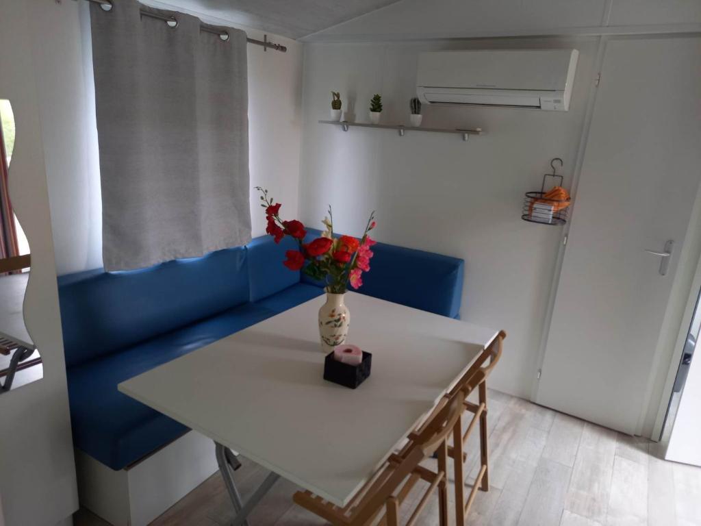 Biały stół z wazonem kwiatów na niebieskiej kanapie w obiekcie Mobilhome 6 pers avec Clim w mieście Saint-Georges-de-Didonne