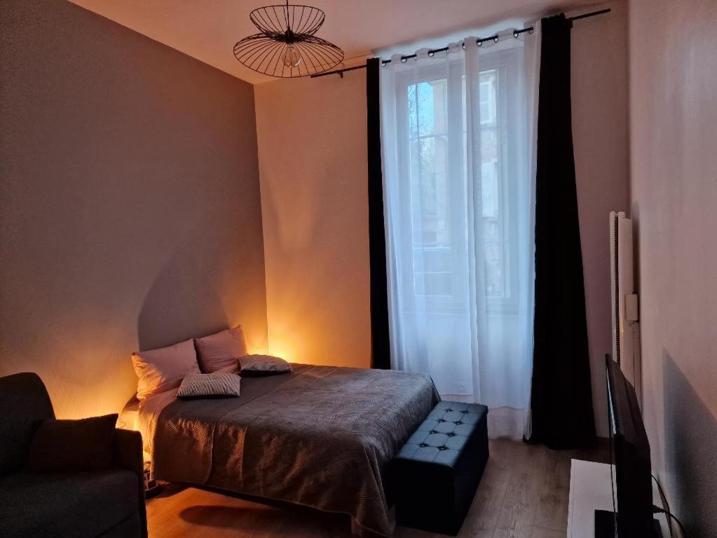 a bedroom with a bed and a large window at appartement cosy en centre ville avec terrasse in Villefranche-sur-Saône