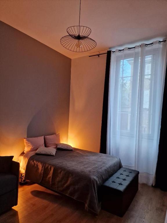 a bedroom with a bed and a large window at appartement cosy en centre ville avec terrasse in Villefranche-sur-Saône