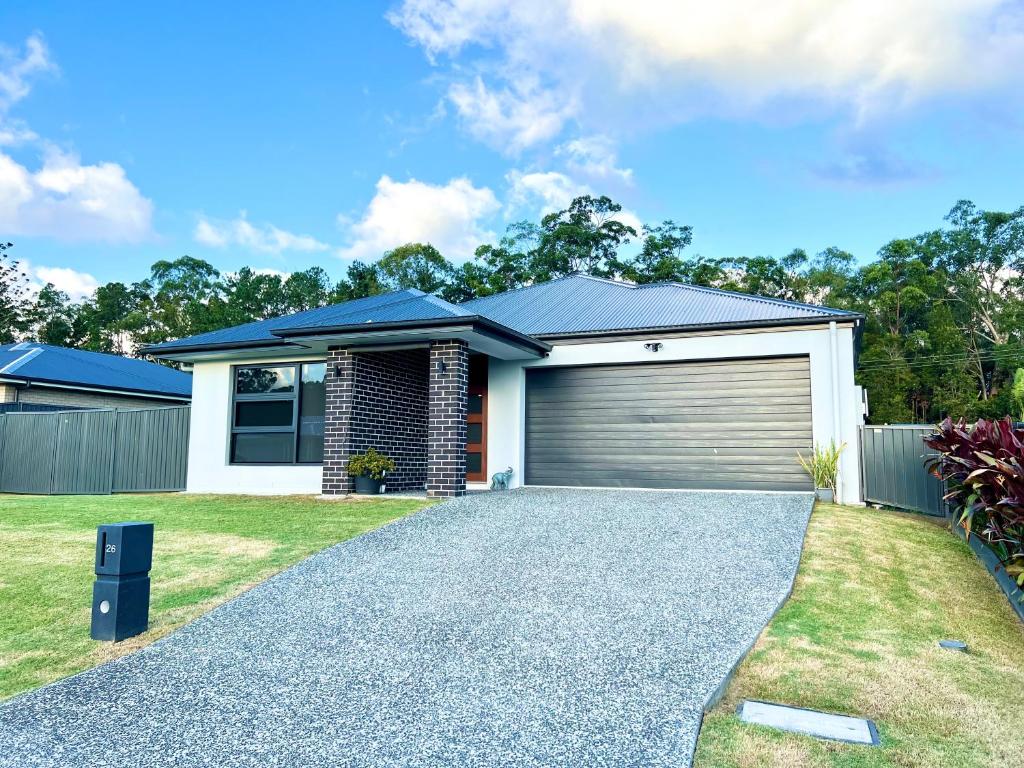 a house with a garage and a driveway at Plantation Retreat 4 Bedroom Modern Home in Landsborough