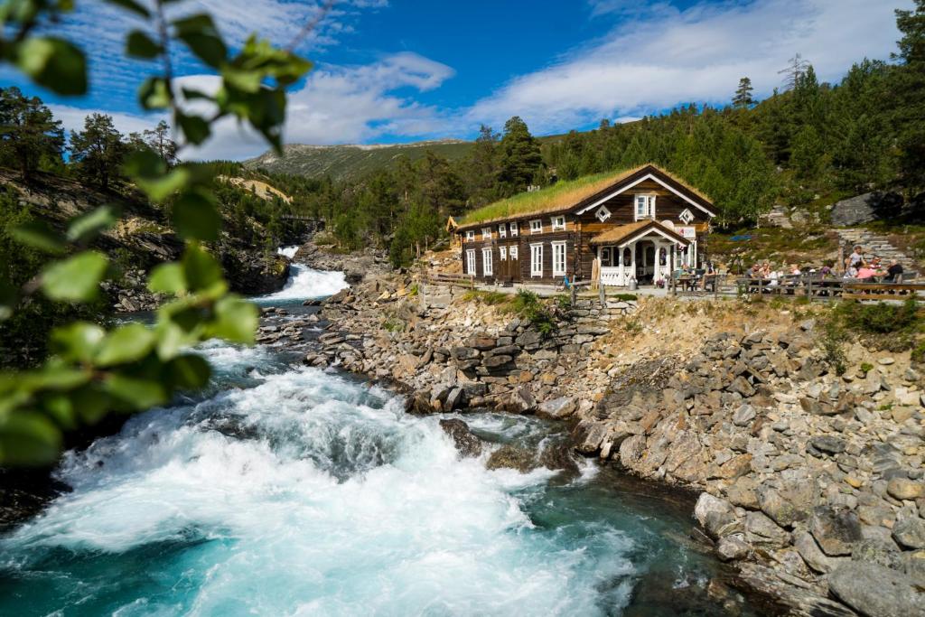 ein Haus am Ufer eines Flusses in der Unterkunft Billingen Seterpensjonat in Skjåk