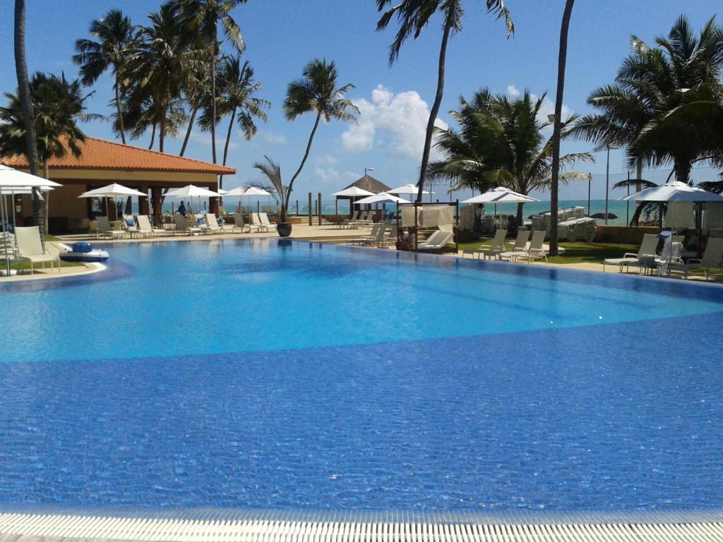 una gran piscina azul junto a la playa en Jatiúca Resort Flat 404 en Maceió