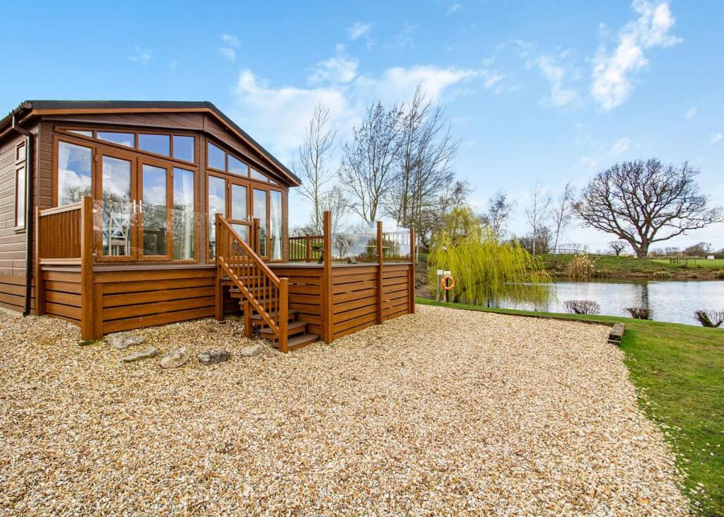 a small cabin with a staircase next to a lake at Camper Uk Leisure Park in Doddington