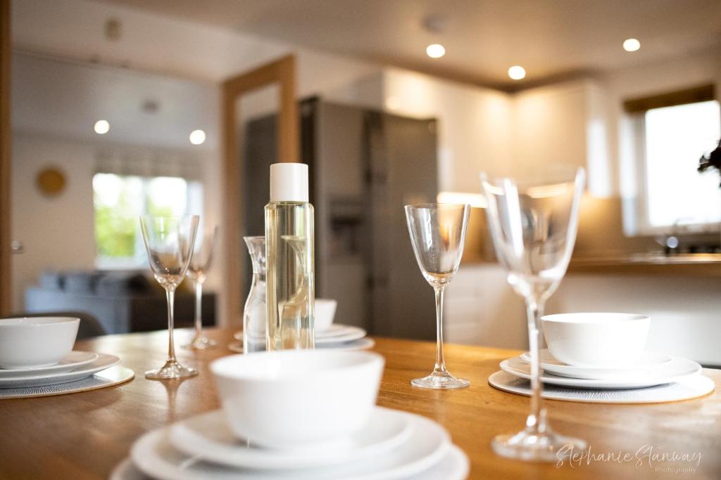 a wooden table with wine glasses and plates on it at The Lookout, Modern Home from Home, Sleeps 5, with private parking & outside terrace in St Ives