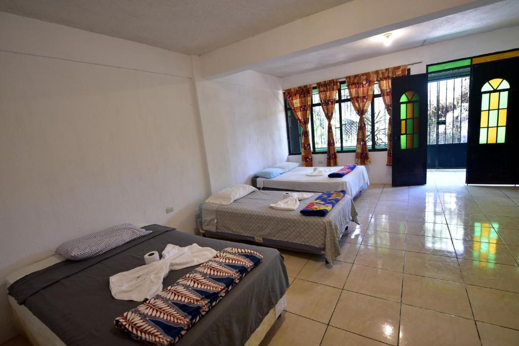 1 dormitorio con 2 camas y 1 dormitorio con ventanas en CASA EL ROBLE, en San Juan La Laguna