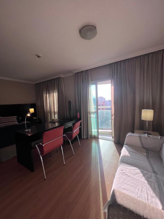 een hotelkamer met een bed en een bureau met stoelen bij HOTEL PERDIZES - FLAT Executivo - 1403 in Sao Paulo
