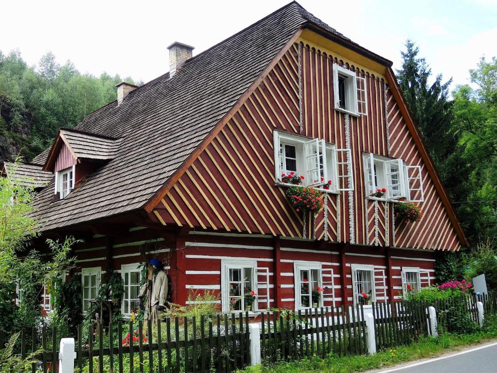 a red house with white windows and a fence at Mlýn u skály in Deštné v Orlických horách