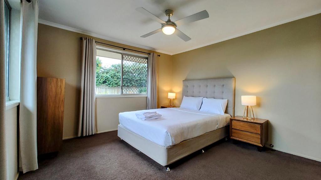1 dormitorio con cama blanca y ventana en Stroll to the City Center in Minutes en Toowoomba