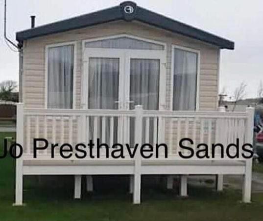 a house with a white fence in front of it at Presthaven Sands Holiday Park 3 and 2 Bed Caravans in Prestatyn