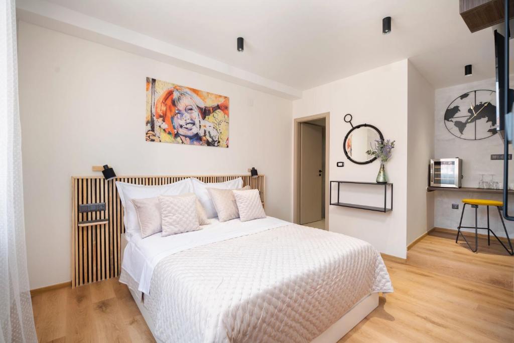 a bedroom with a large white bed and a painting on the wall at Hygge Rooms Split in Split