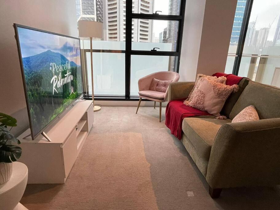 ein Wohnzimmer mit einem TV, einem Sofa und einem Stuhl in der Unterkunft City Haven with Breathtaking Views in Melbourne