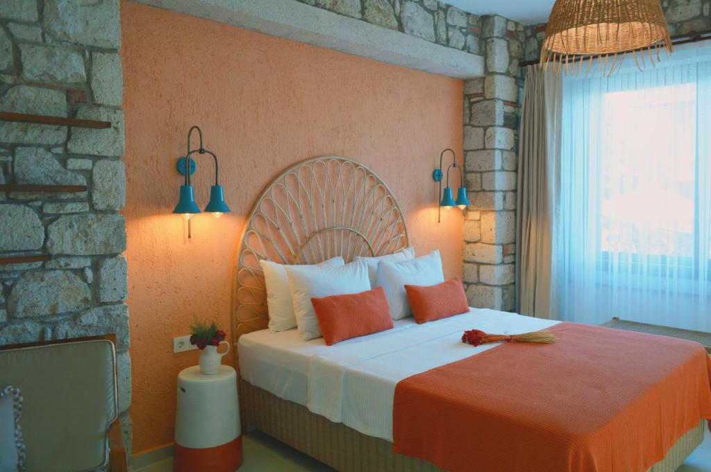 a bedroom with a large bed with orange and white pillows at Rijeka Alaçatı in Cesme