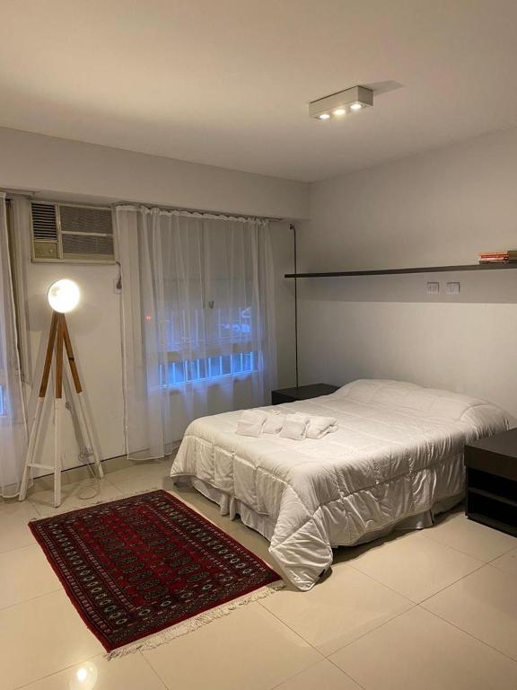 a bedroom with a white bed and a red rug at Boutique Studio Recoleta in Buenos Aires