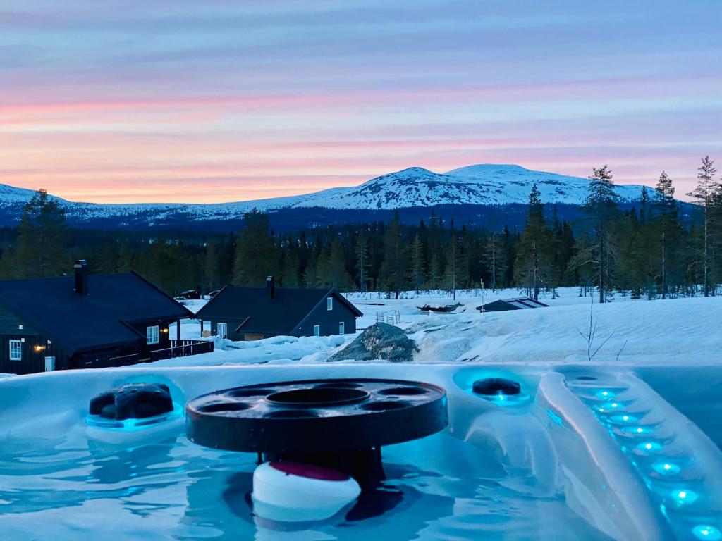 a snow covered yard with a snow covered mountain in the background at Hytte Trysil SPA in Trysil