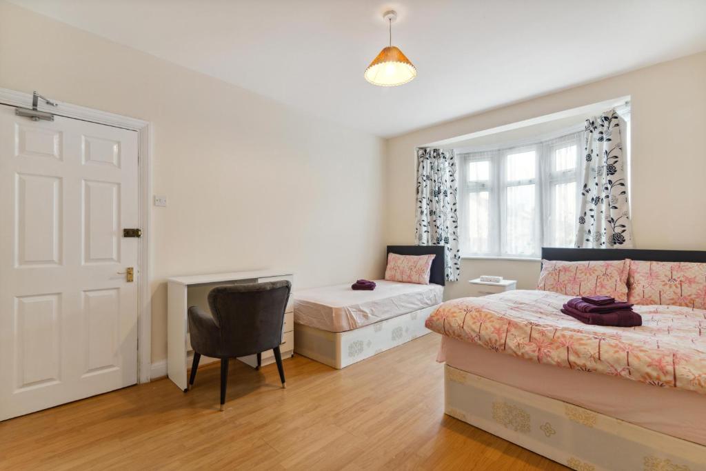 sypialnia z 2 łóżkami, krzesłem i drzwiami w obiekcie Beautiful Cozy Room w Londynie