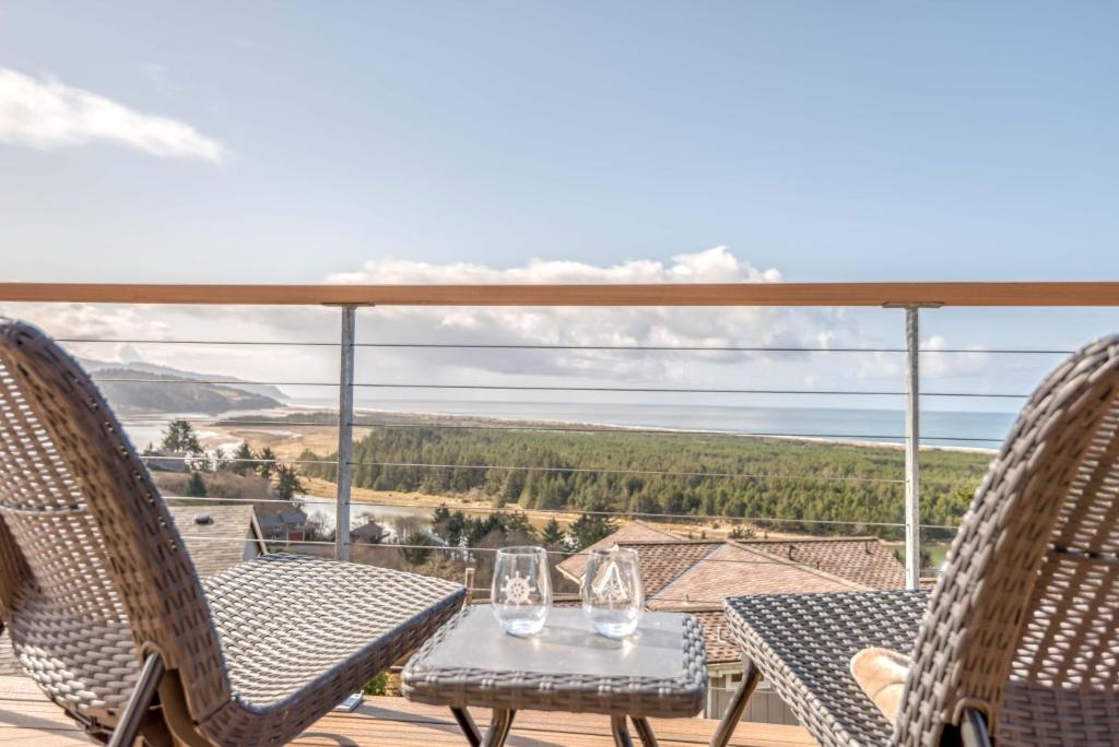 un patio con 2 sillas y una mesa con copas de vino. en Summit Lighthouse - Meredith Lodging, en Pacific City