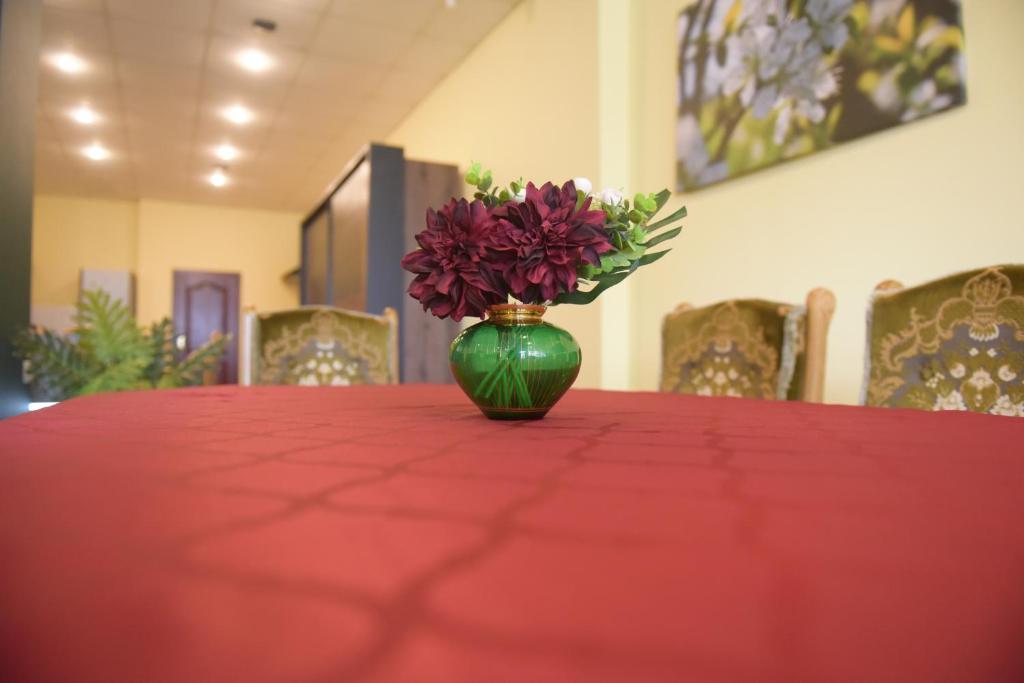 Apartament w Rynku في Pitschen: مزهرية خضراء مع الزهور موضوعة على طاولة حمراء