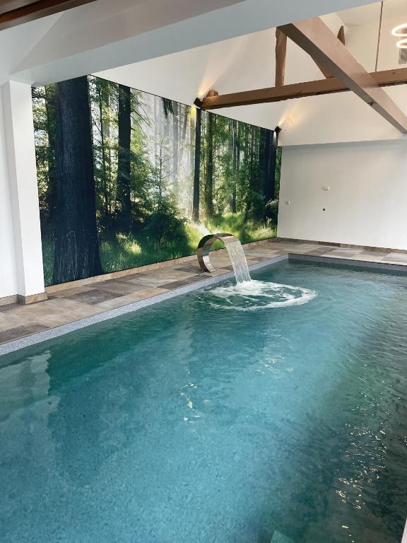 a swimming pool with a water fountain in a house at A la ferme in Kurtzenhouse
