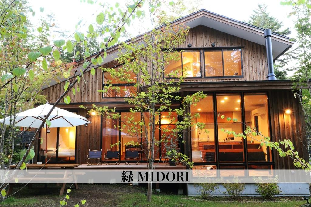 una casa con puertas de cristal y porche en Karuizawa Forest Seasons Villa, en Karuizawa