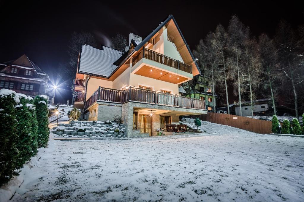 a house in the snow at night at Willa Azja SPA & Wellness in Zakopane