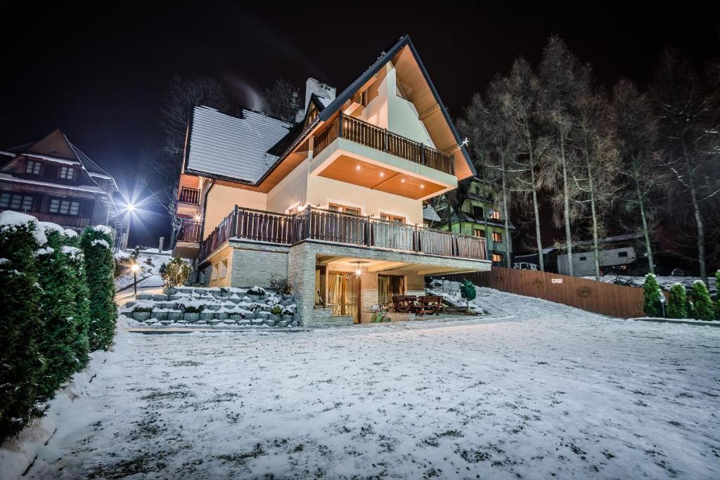 uma casa na neve à noite em Willa Azja SPA & Wellness em Zakopane