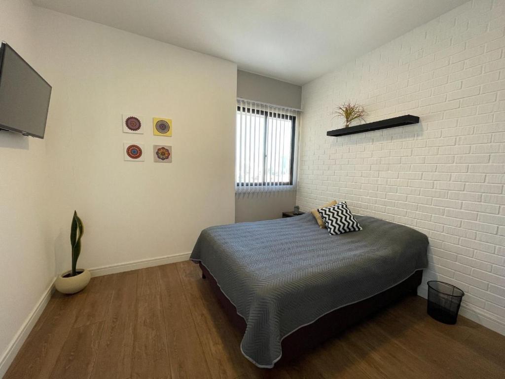 - une chambre avec un lit et un mur en briques dans l'établissement SPACE BOX, à Cochabamba