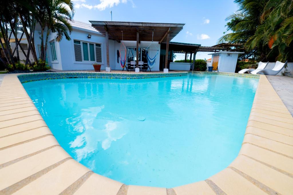 a swimming pool with blue water in front of a house at Caribbean Backyard - Home w Private Pool/Jacuzzi in Aguada