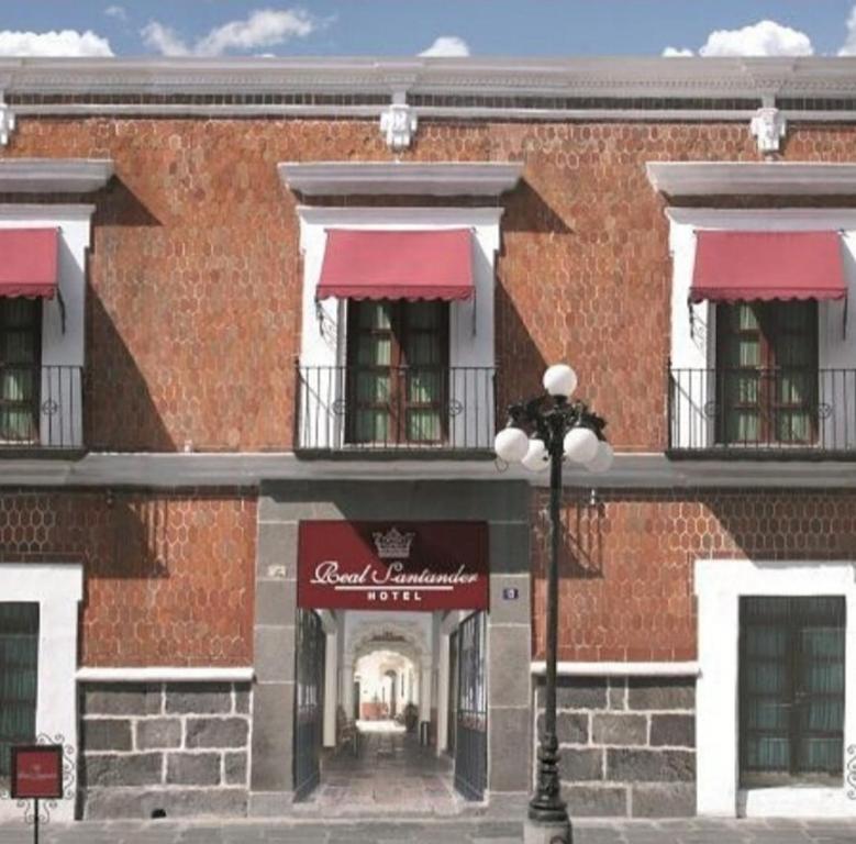 un gran edificio de ladrillo con toldos rojos y luz de la calle en Hotel Real Santander, en Puebla