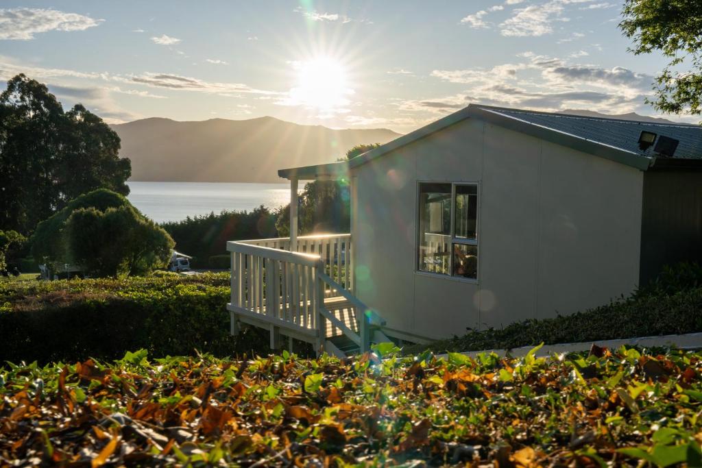 a tiny house with the sun in the background at Akaroa Top 10 Holiday Park in Akaroa