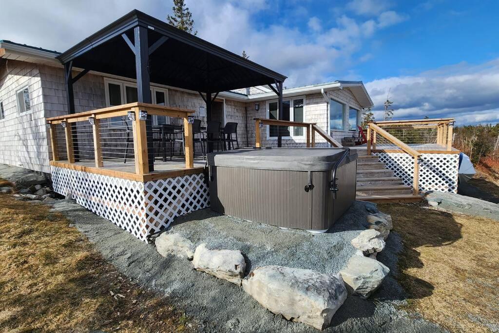 une maison avec une terrasse et un bain à remous dans l'établissement Serenity Oceanview Retreat, 