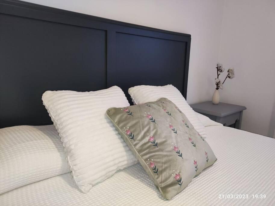een wit bed met 2 kussens en een zwart hoofdeinde bij Casa Dina in Carballino