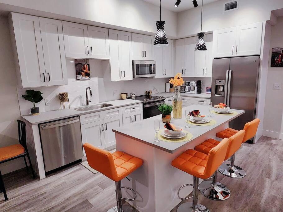 a kitchen with white cabinets and an island with orange chairs at Luxe & cozy 3Beds,2rooms,EV Gym Near Beaches&Downtown WPB in West Palm Beach