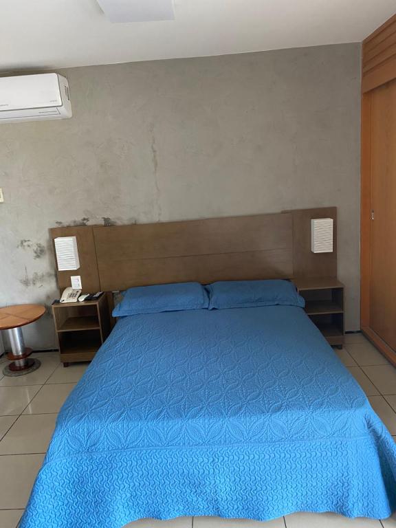 - un lit avec une couette bleue dans une chambre dans l'établissement Flat com vista para o Mar, à Fortaleza